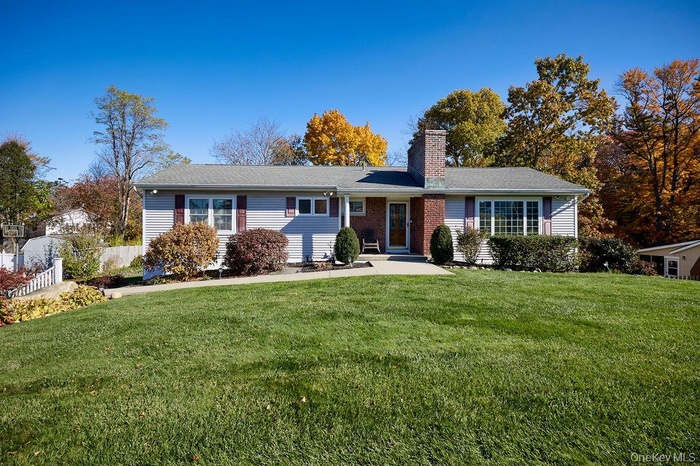Ranch-style house with a front lawn, a chimney, and brick siding