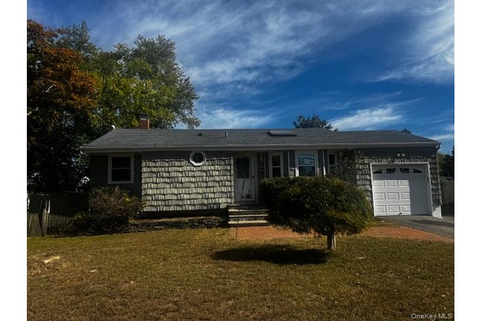 Ranch-style house featuring a front yard, an attached garage, driveway, and a chimney