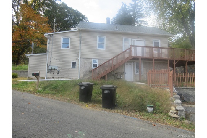Rear view of property featuring a wooden deck, stairs, and a chimney