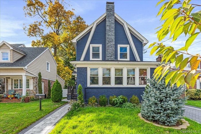 View of front of home with a chimney, a front lawn, and a porch