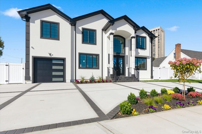 View of front facade featuring a gate, driveway, stucco siding, and a garage