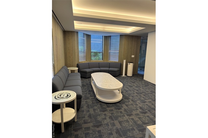 Living room with a tray ceiling, wood walls, and dark carpet