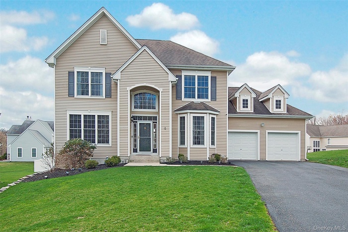 Traditional-style home with driveway, a front lawn, and an attached garage
