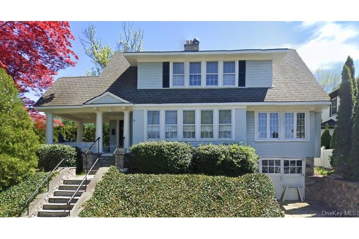 View of front facade featuring a garage, a chimney, stairway, a porch, and a shingled roof