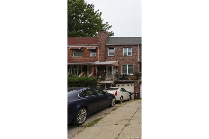Traditional home featuring brick siding, a garage, driveway, and a chimney