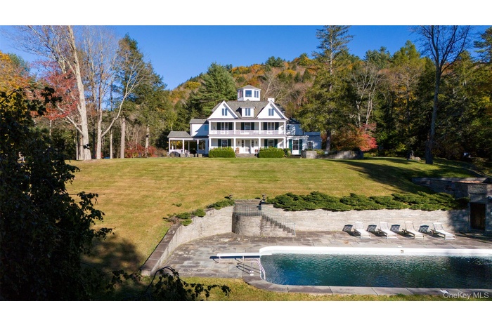 Back of house featuring a patio area, a yard, an outdoor pool, and a balcony