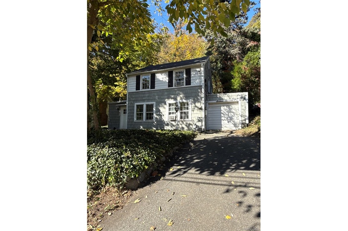 View of front facade with asphalt driveway, an outbuilding, and a garage