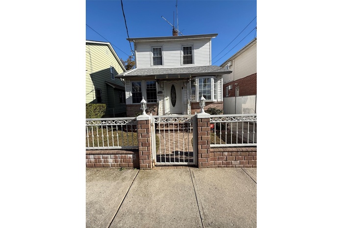 View of front of property with a gate, a fenced front yard, brick siding, and a chimney