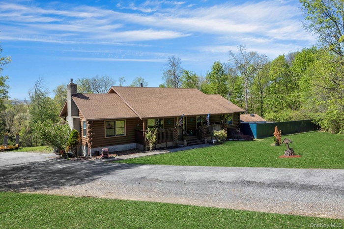 Log home featuring a chimney, log siding, covered porch, roof with shingles, and a front lawn