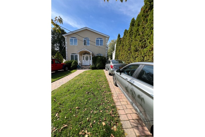 Traditional-style house with stucco siding and a front lawn