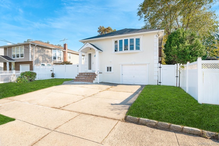 View of front of property with driveway, an attached garage, a gate, and stucco siding