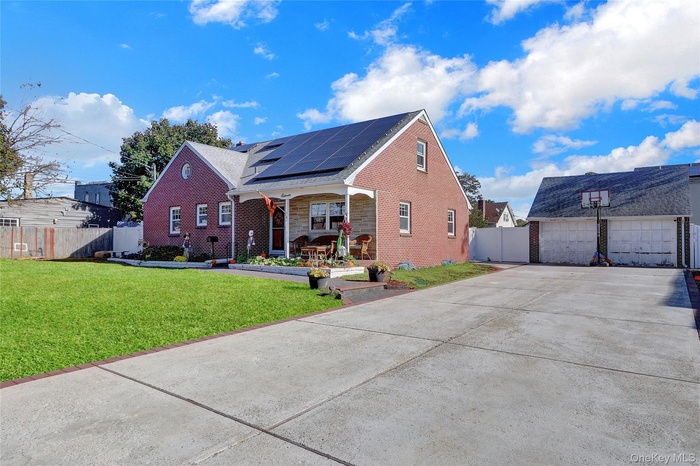 View of front facade with a porch, solar panels, brick siding, and a detached garage