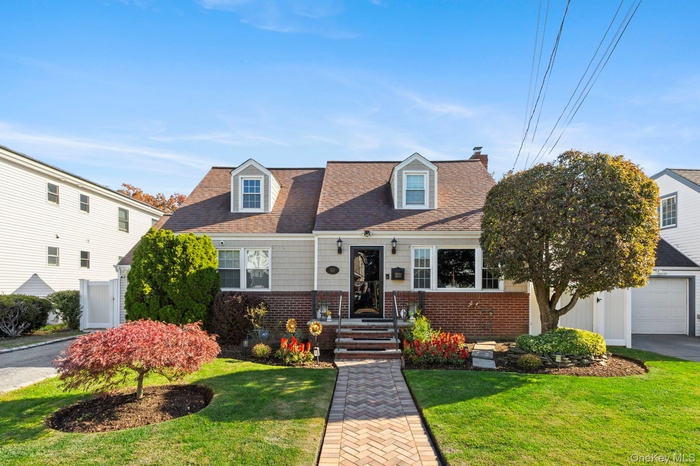 Cape cod home featuring brick siding, a shingled roof, a front lawn, and a chimney