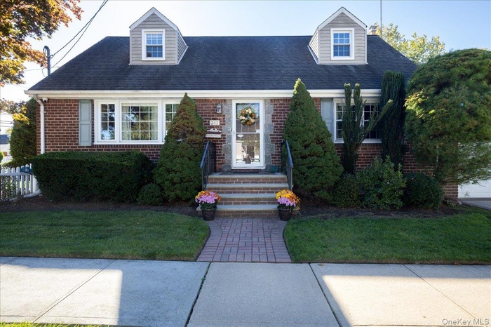 Cape cod home with brick siding, a front lawn, and roof with shingles