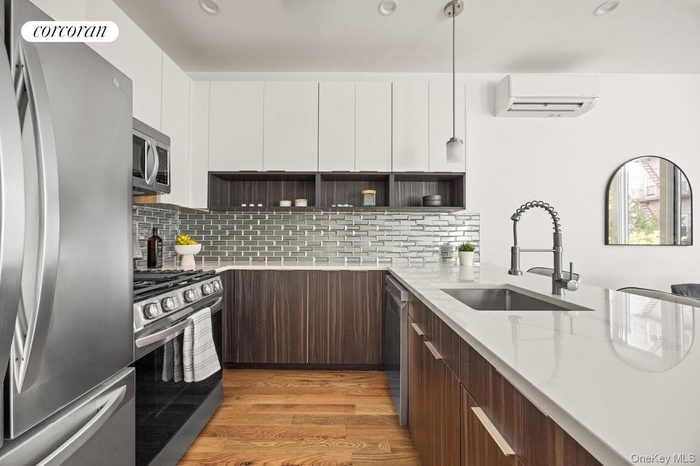 Kitchen with modern cabinets, appliances with stainless steel finishes, dark brown cabinetry, light wood-style floors, and recessed lighting