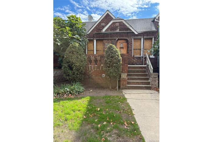 View of front of home featuring brick siding and roof with shingles