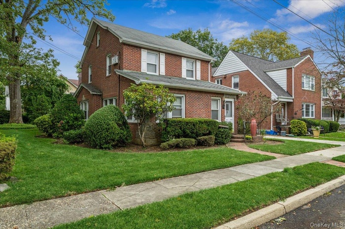 Traditional-style house featuring brick siding and a front yard