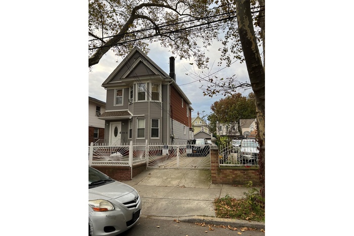 View of front of home with a fenced front yard, a chimney, and a gate