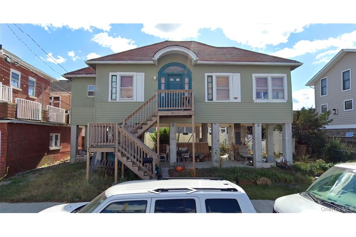 View of front of property with a patio, stairway, a shingled roof, and stucco siding