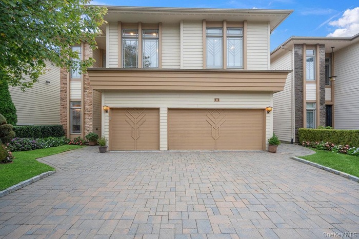 View of front of house with decorative driveway and a garage