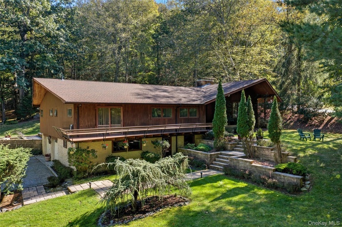 View of front facade featuring a front lawn, brick siding, a balcony, and roof with shingles