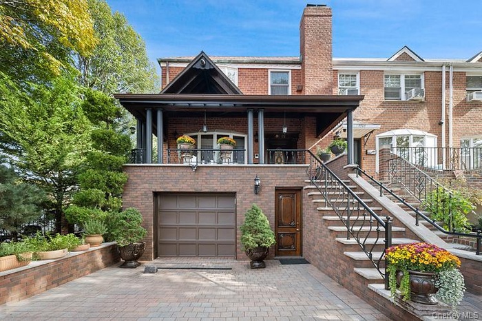 View of front of home featuring a chimney, brick siding, stairs, and driveway