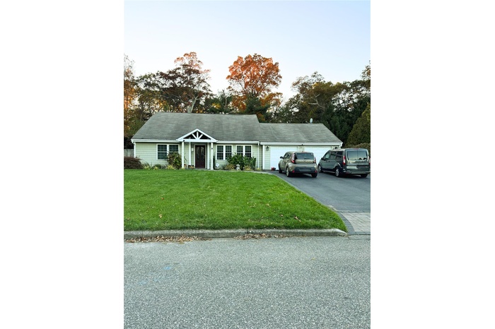 View of front of home with a front lawn, asphalt driveway, and an attached garage