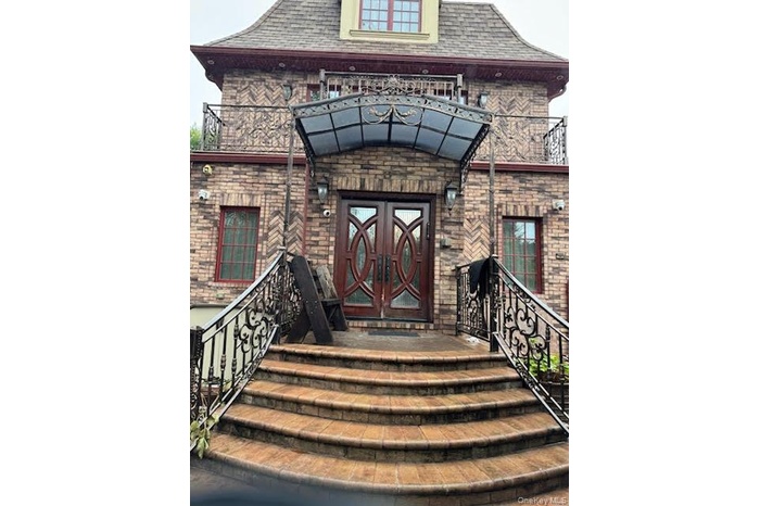 View of exterior entry featuring brick siding and a shingled roof