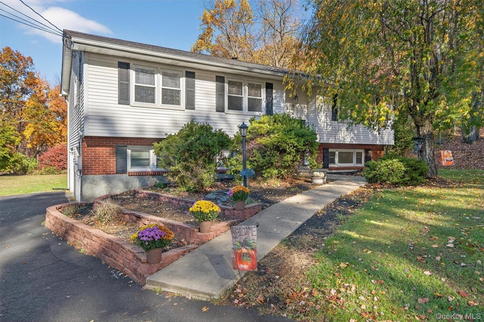 Split foyer home with brick siding and a front lawn