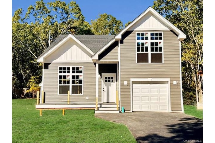 View of front of house with board and batten siding, a front lawn, a garage, and driveway