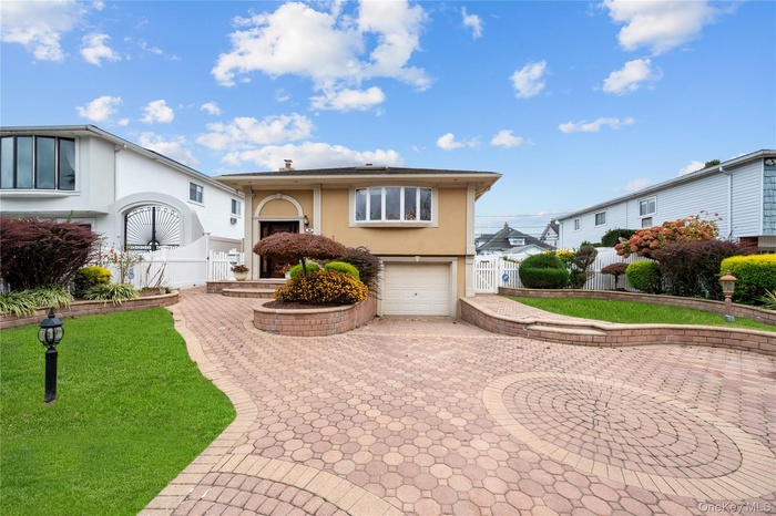 View of front of home featuring stucco siding, an attached garage, decorative driveway, and a gate
