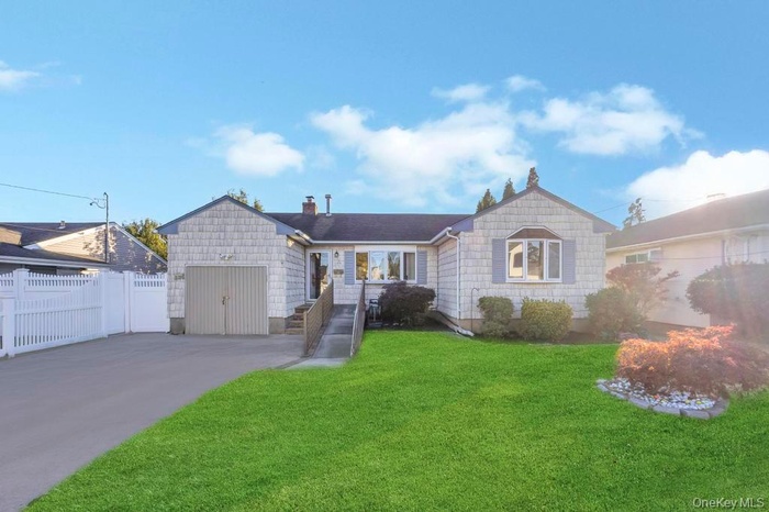 Single story home with a chimney, driveway, and a garage