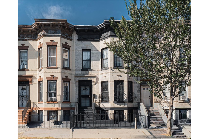 Italianate home with brick siding and a fenced front yard
