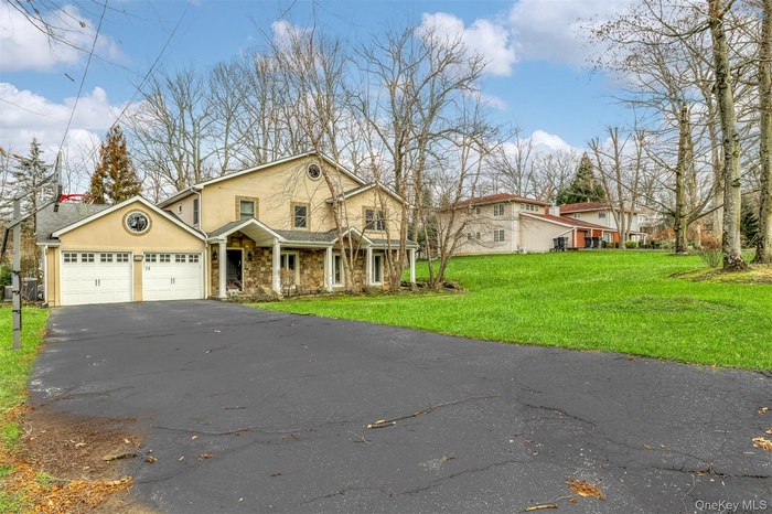 View of front facade with covered porch, stucco siding, a front yard, and driveway