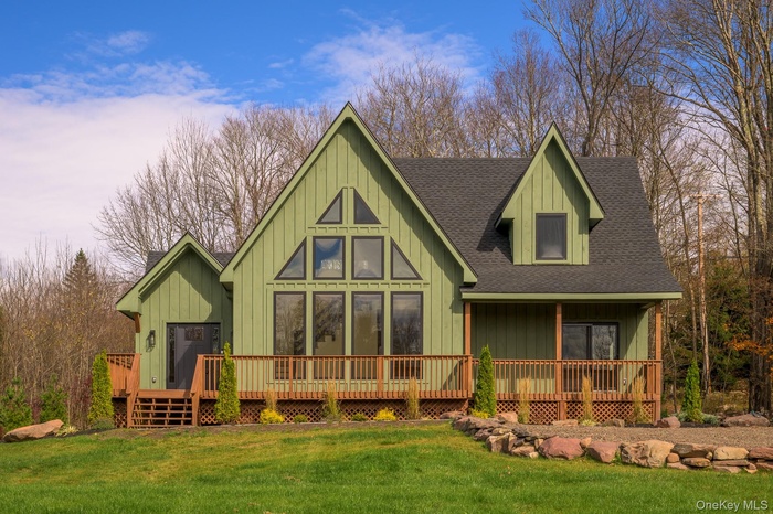 Rear view of house featuring a shingled roof, board and batten siding, a lawn, and covered porch