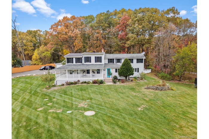 Back of property featuring a porch, a lawn, and a chimney