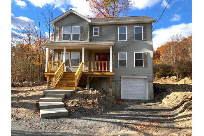 View of front facade with covered porch, driveway, stairs, and an attached garage