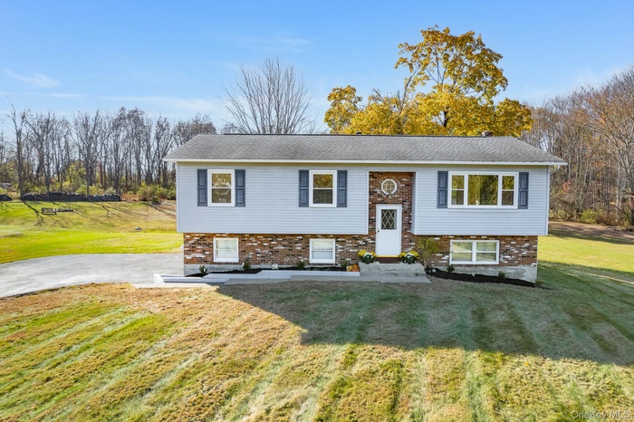 Split foyer home with a front yard and brick siding