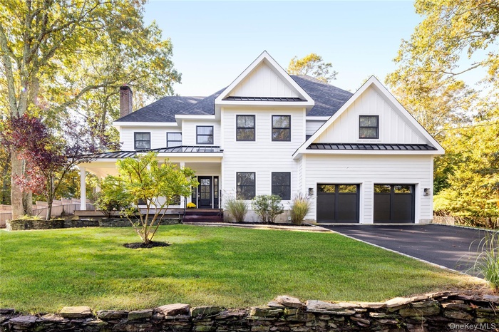 Modern inspired farmhouse featuring a standing seam roof, a metal roof, and a porch