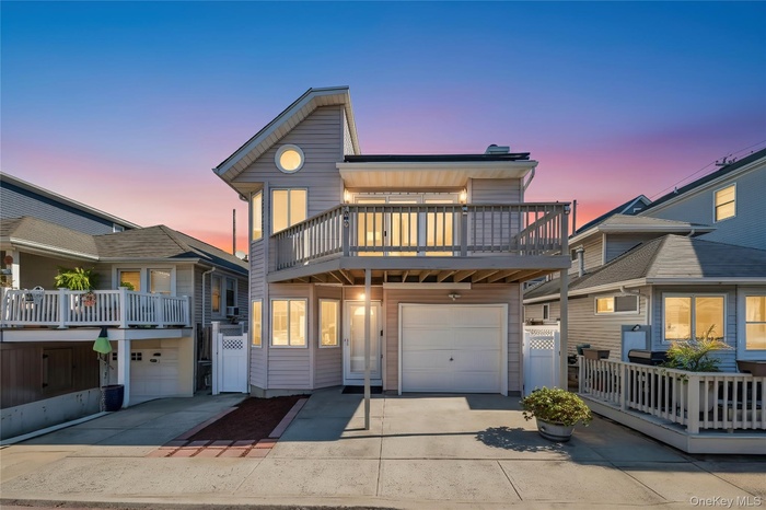 View of front facade with an attached garage, driveway, and a wooden deck