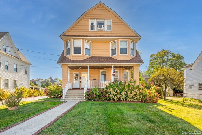 View of front of home featuring a front lawn, a porch, and a shingled roof