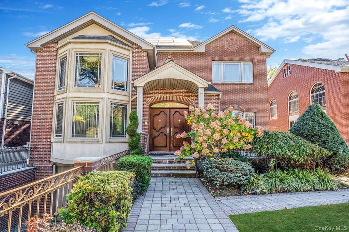 Entrance to property featuring roof mounted solar panels and brick siding