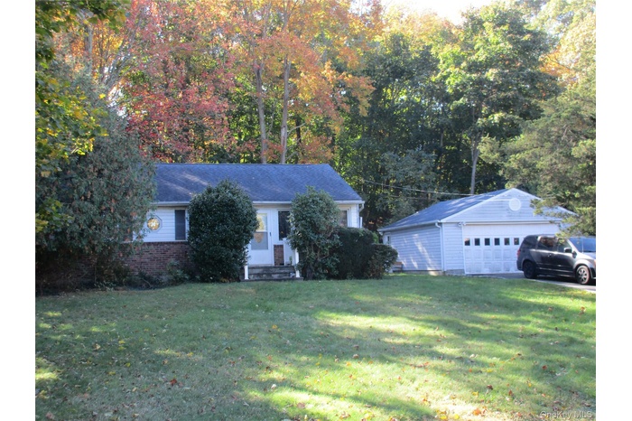 View of front of house featuring an outdoor structure, a front lawn, a detached garage, and brick siding
