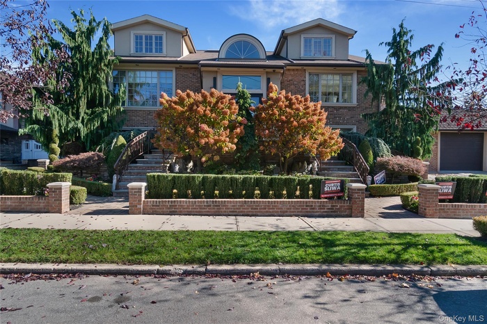 View of front facade with stairway, brick siding, and stucco siding