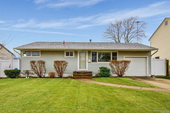 Ranch-style home with an attached garage, concrete driveway, and roof with shingles