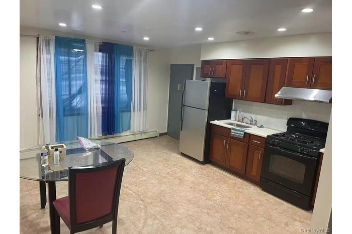 Kitchen featuring black range with gas stovetop, light countertops, under cabinet range hood, recessed lighting, and freestanding refrigerator