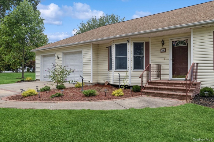 View of front of house featuring a front yard, a shingled roof, concrete driveway, and a garage