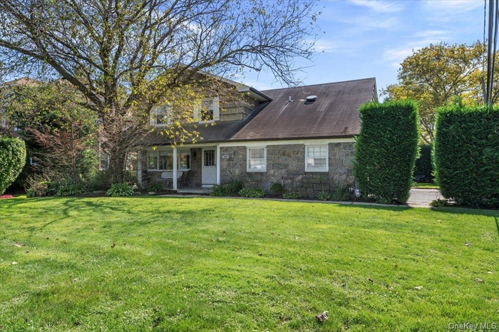 View of front of house with stone siding, a front yard, and a patio area