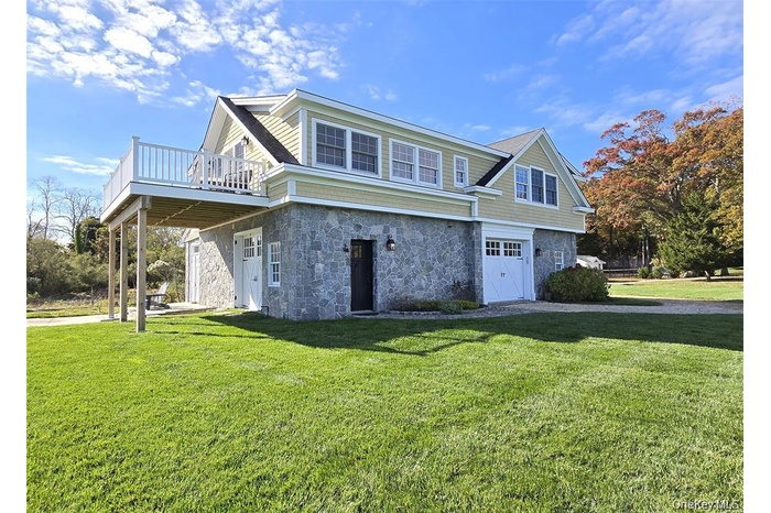 View of front of house with stone siding, a front lawn, a patio, and a garage