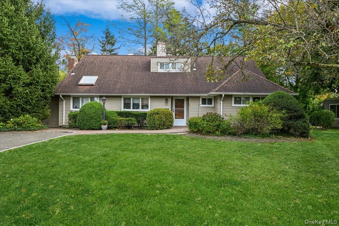 View of front of home with a front yard, a chimney, and a shingled roof